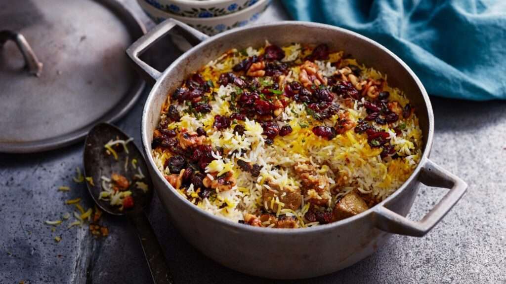 Kashmiri Mutton Dum Biryani is among the types of biryani that is served in an iron pot with raisin garnishing and scooped from one side.
