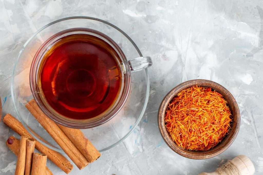 How to make saffron water? A cup of saffron water/tea with saffron threads on the side.